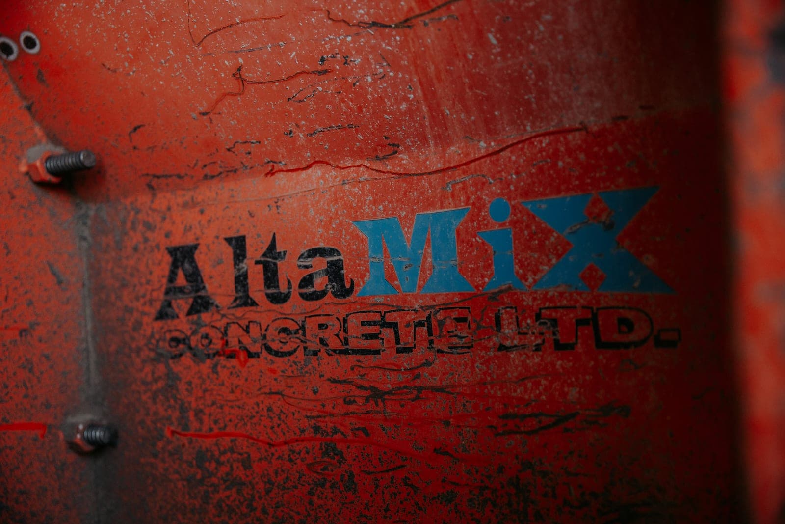 The weathered AltaMix Concrete Ltd. logo painted on a red concrete mixer drum.