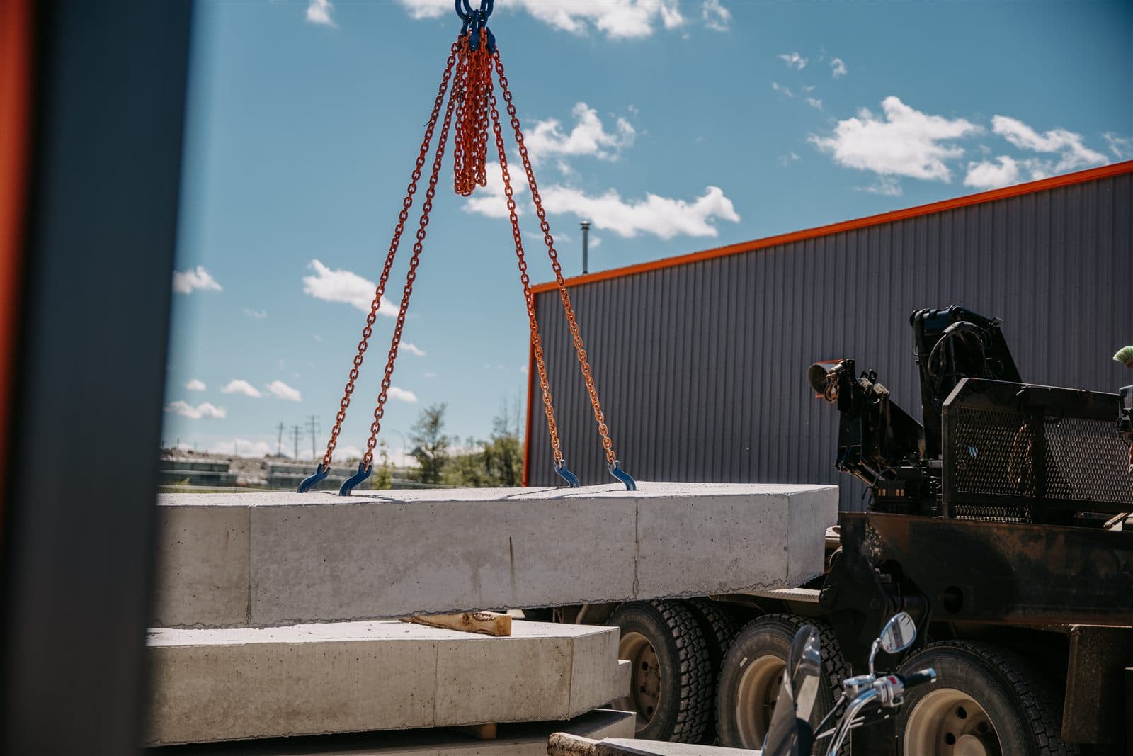 An AltaMix crane truck lifting a flat precast pad off the flat-deck trailer.