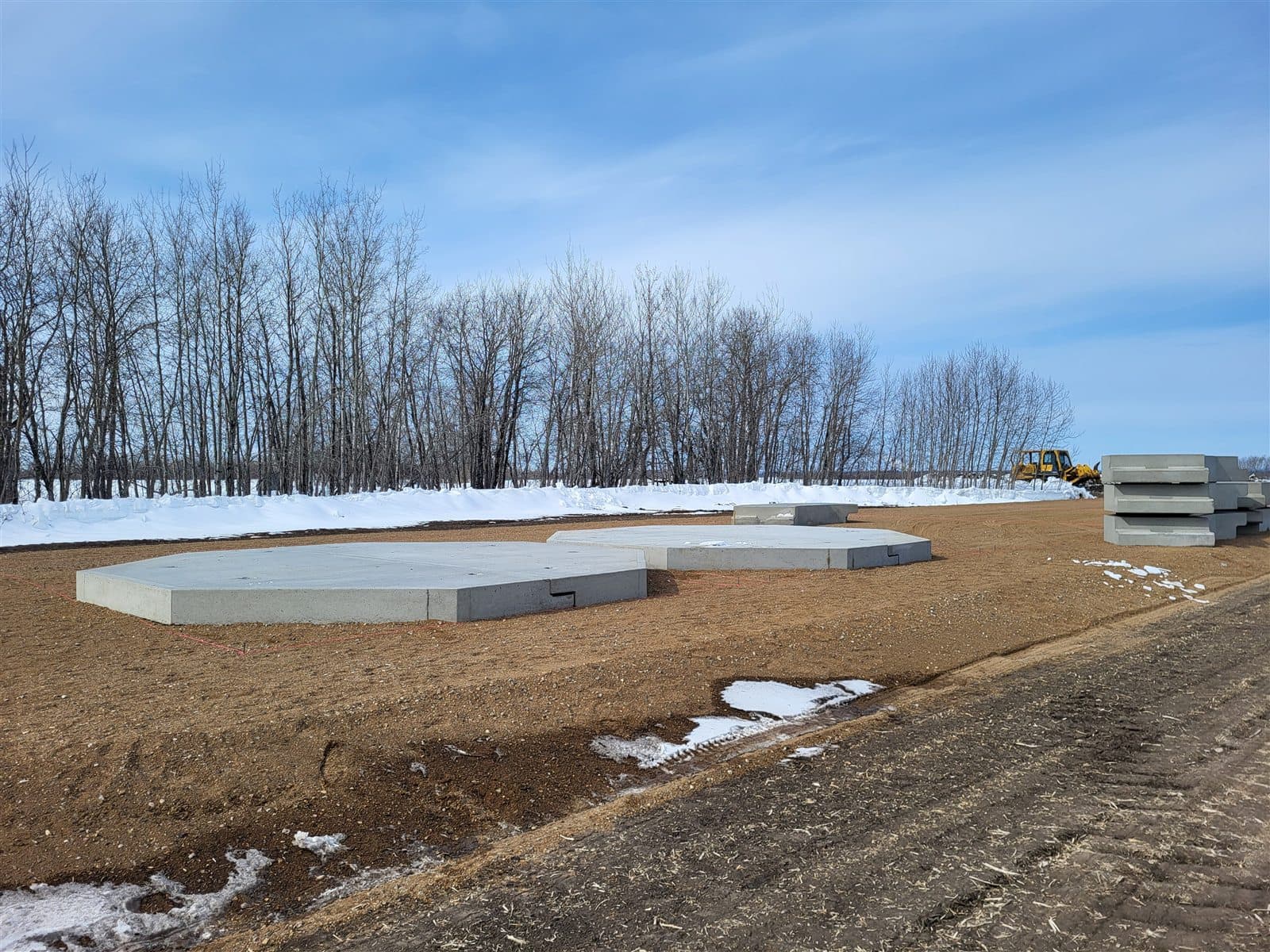 Octagonal AltaMix precast water pads set out in a field, with extra pads stacked nearby.